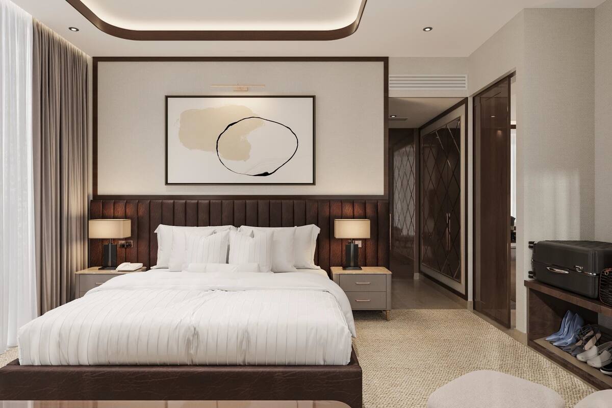 A hotel room with a large bed, bedside tables, a wall-mounted artwork, and a shoe rack.