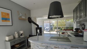Een moderne keuken met een achterwand van steen, een koffiezetapparaat en een groot raam met uitzicht op een tuin.