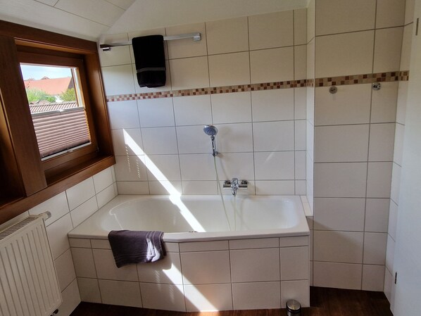 Ein Badezimmer mit einer Badewanne, einem Fenster und einem Handtuchhalter.