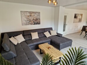 A modern living room with a sectional sofa, a wooden coffee table, and two abstract paintings on the walls.