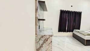 Un dormitorio con cama, pared decorativa de mármol, cortina oscura y ventana pequeña.