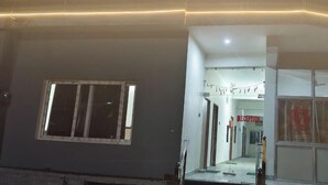 Una entrada de edificio con recepción, un ventanal y un cartel.