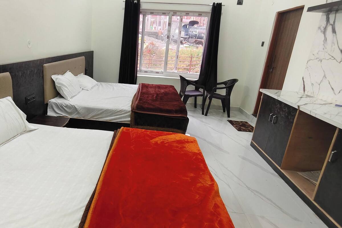 Habitación de hotel con dos camas, un escritorio y una ventana con vistas al exterior.
