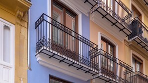 A multi-story building with balconies, a ground-level entrance, and a visible sign indicating a business on the ground floor. - Mon Suites Platería (Valencia)