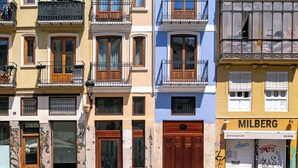 Una hilera de edificios de varios pisos con balcones, una tienda en la planta baja y un letrero que dice 'MILBERG'.
