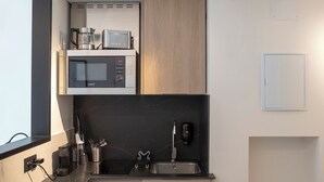 Una cocina compacta con microondas, cafetera y un refrigerador pequeño.