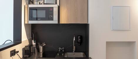 A compact kitchen with a microwave, coffee maker, and a small refrigerator.