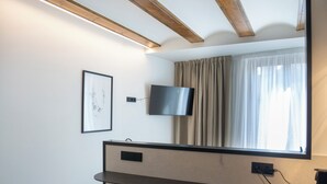 A modern room with a wooden ceiling, a flat-screen TV mounted on the wall, a window with curtains, and two stools at a counter. - Mon Suites Platería (Valencia)