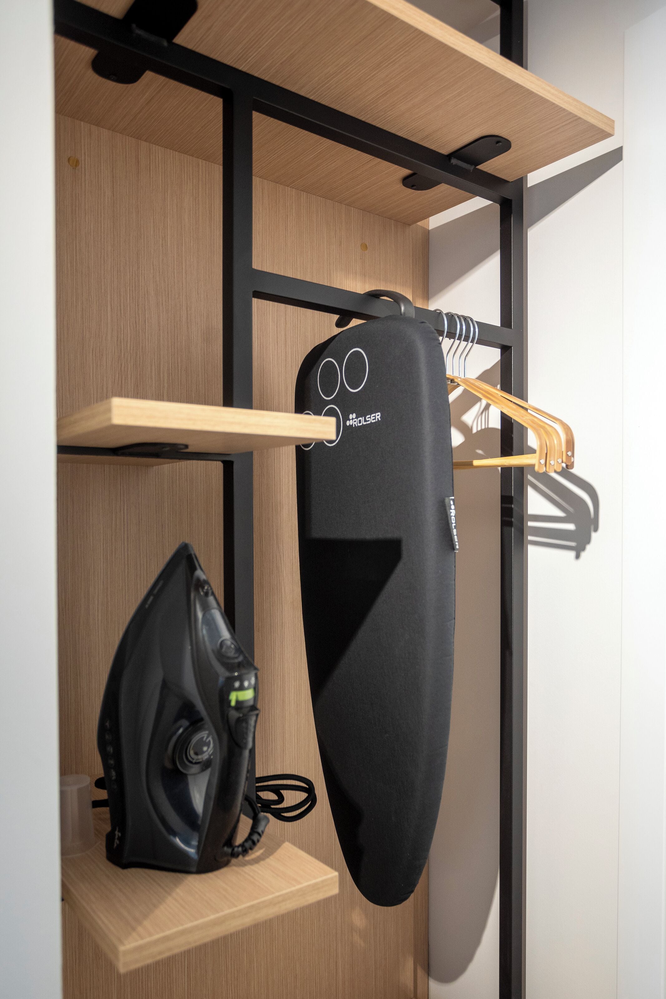 Ein kleiner Raum mit einer Holzwand, einem schwarzen Gerät auf einem Regal und einer schwarzen Tasche.