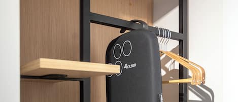 A compact room with a wooden wall, a black device on a shelf, and a black bag.