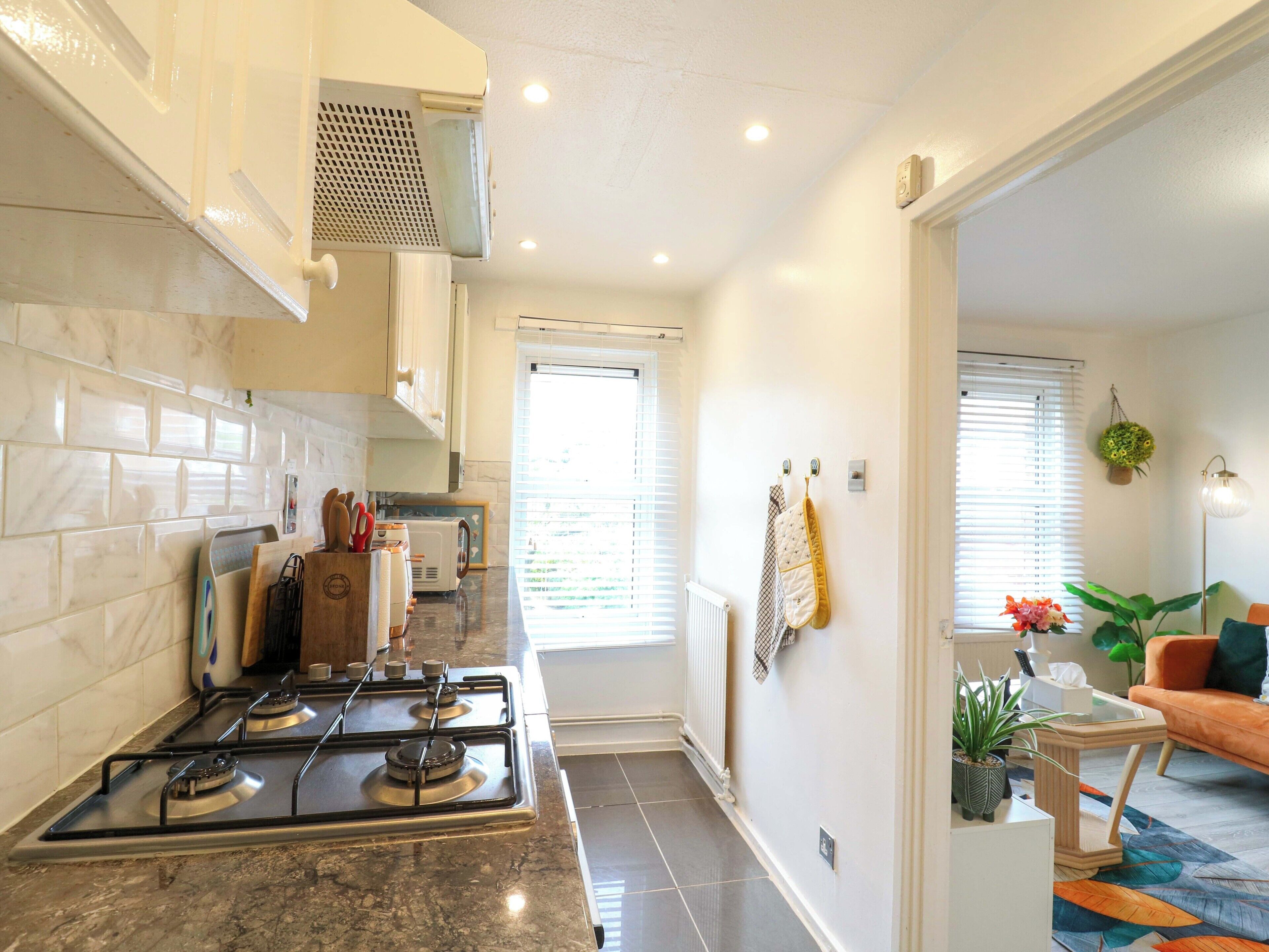 A kitchen with a stove, microwave, and cabinets, leading to a living area with a sofa and a coffee table.
