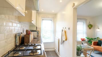 A kitchen with a stove, microwave, and cabinets, leading to a living area with a sofa and a coffee table.