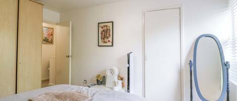 A bedroom with a bed, a mirror, a door, and a wall-mounted picture.