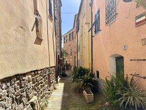 A narrow street with stone walls and buildings with shutters and signs. - Tery’s Apartment (Imperia)