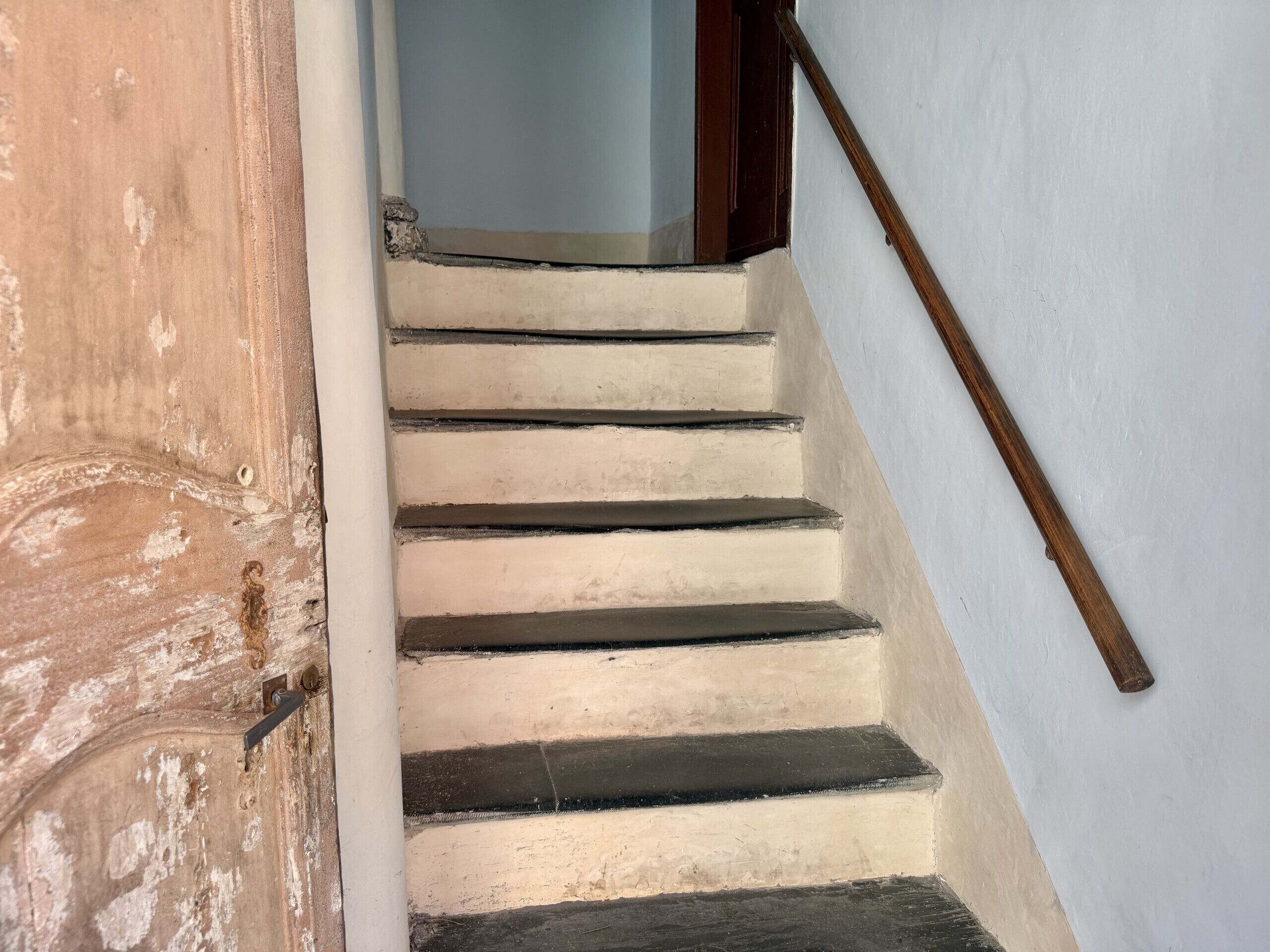 Eine Treppe mit einem Holzgeländer und einer Tür zu einem Raum.