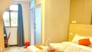 A hotel room with a bed, a chair, a window with curtains, and a door. - LIAZONS HOTEL NAKURU (Nakuru)