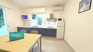 Una cucina compatta con zona pranzo, TV e frigorifero.