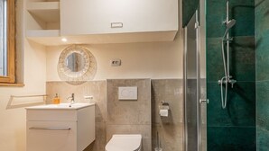Casa de banho moderna com sanita, lavatório e chuveiro.