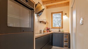 Uma cozinha compacta com geladeira embutida, uma janela e teto de madeira.