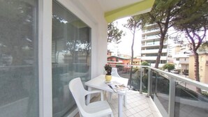 A balcony with a table and chairs, a potted plant, and a view of buildings. - Comfortable central stay with terrace (Lignano Sabbiadoro)