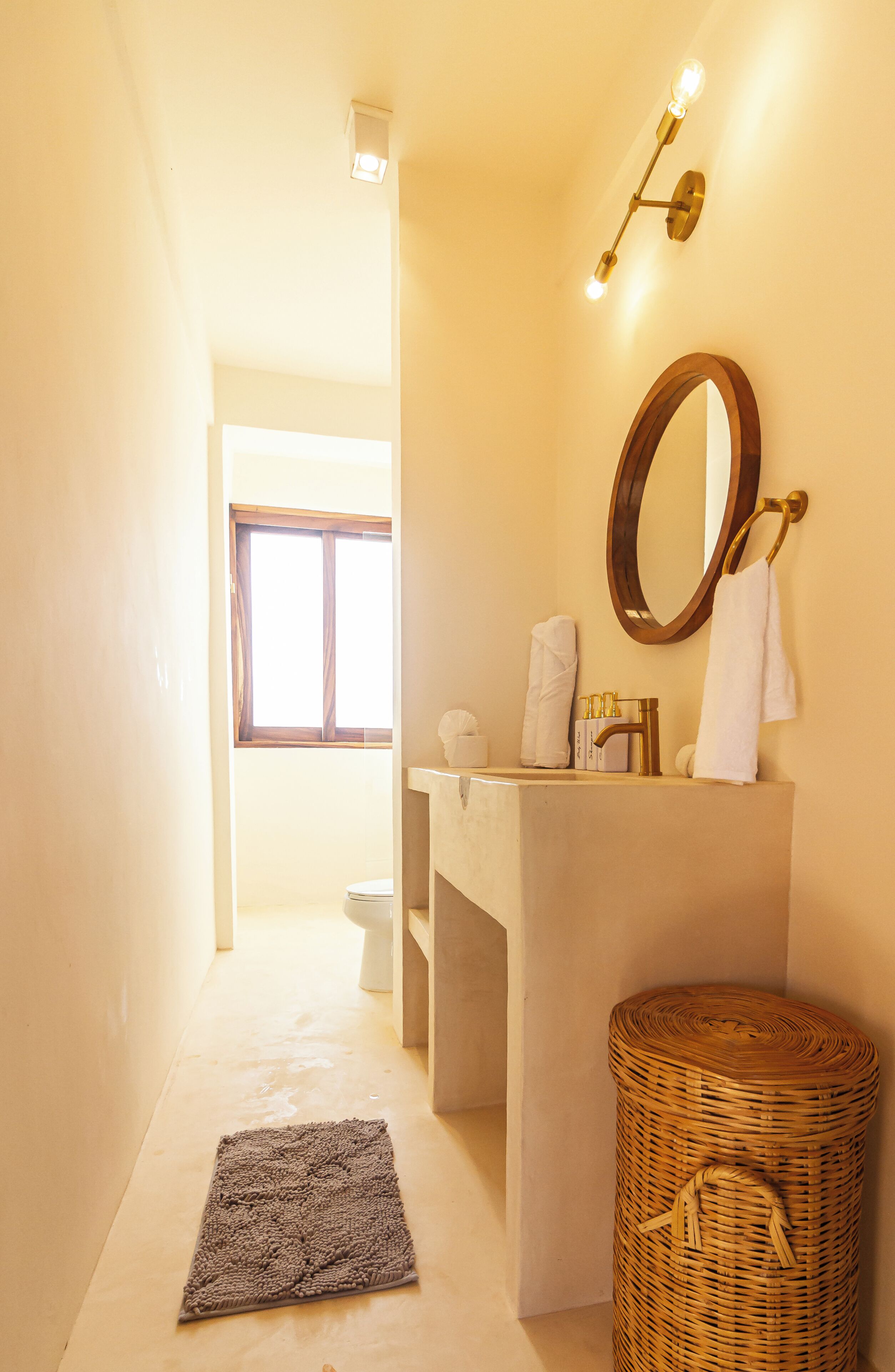 A bathroom with a large mirror, a sink, and a window.