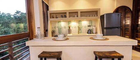 A modern kitchen with a central island, bar stools, and a refrigerator.