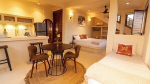 Habitación de hotel compacta con kitchenette, comedor, cama y baño pequeño.