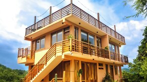 Un edificio de dos pisos con un balcón de madera, una escalera y un gran ventanal.