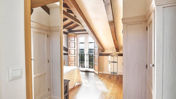 A room with a sloped ceiling, wooden beams, a bed, a table, and a chair. - Casa Taté in Trasvía, Comillas — Space and serenity to share (Trasvía, Comillas)