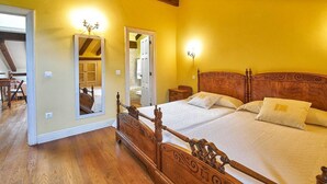 A bedroom with a wooden bed, a mirror, and a door leading to another room. - Casa Taté in Trasvía, Comillas — Space and serenity to share (Trasvía, Comillas)