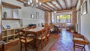 A dining area with wooden furniture, a chandelier, and a view through a window. - Casa Taté in Trasvía, Comillas — Space and serenity to share (Trasvía, Comillas)