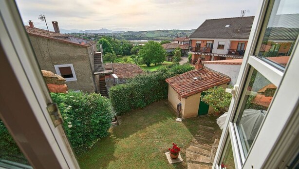 A courtyard with a small garden, a stone pathway, and a view of surrounding buildings.