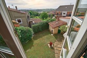 A courtyard with a small garden, a stone pathway, and a view of surrounding buildings.