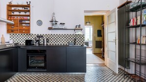 Eine Küche mit Schachbrettboden, einem eingebauten Backofen und einem Holzbodenregal mit Küchenutensilien.