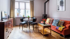 Ein modernes Wohnzimmer mit einer Couch, einem Esstisch, Stühlen, einem Fernseher und einem Kamin.