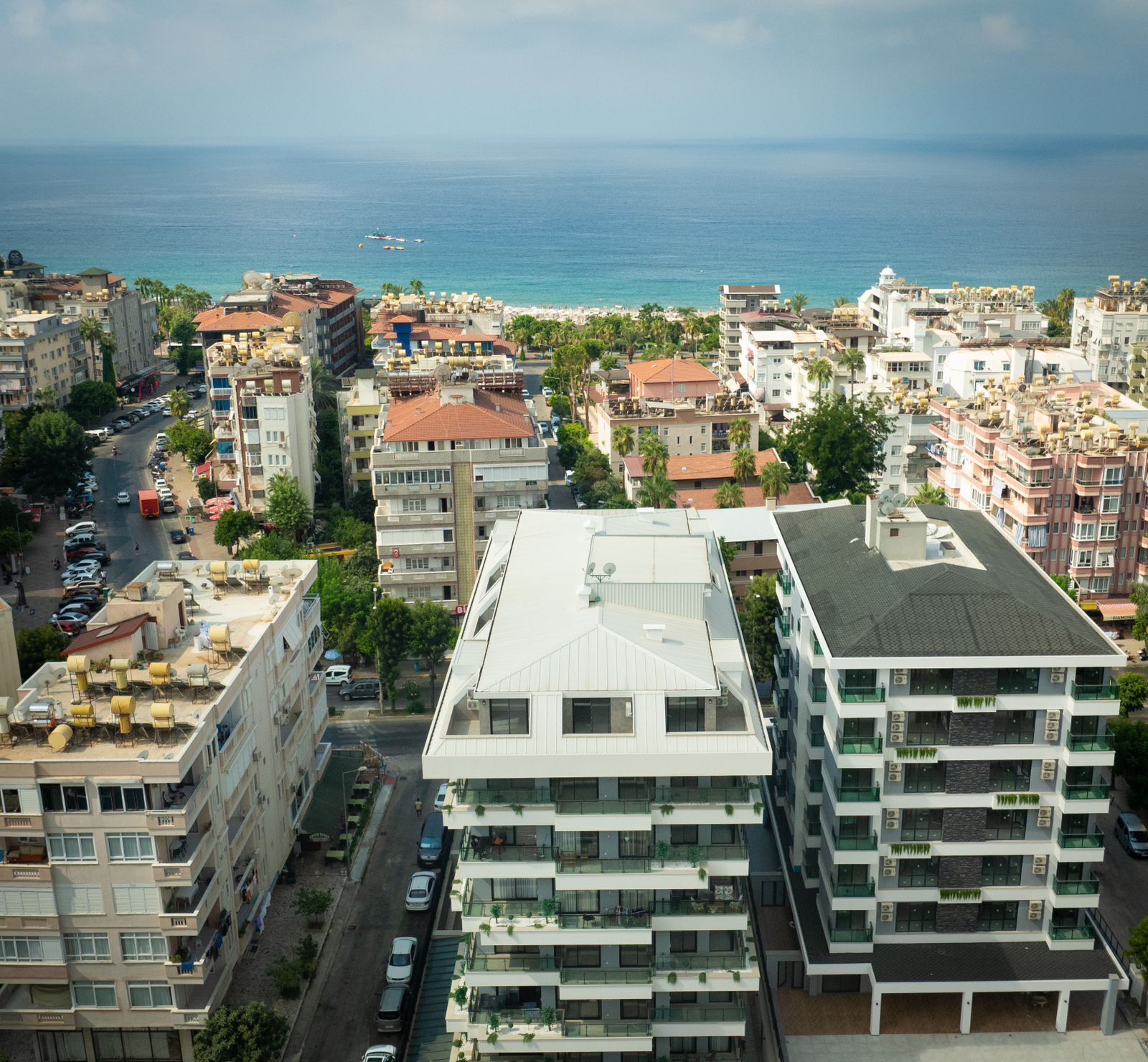 Un paysage urbain côtier avec des bâtiments modernes, une plage et la mer en arrière-plan.