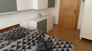 A bedroom with a bed, a bedside table, a wardrobe, and a wooden door.