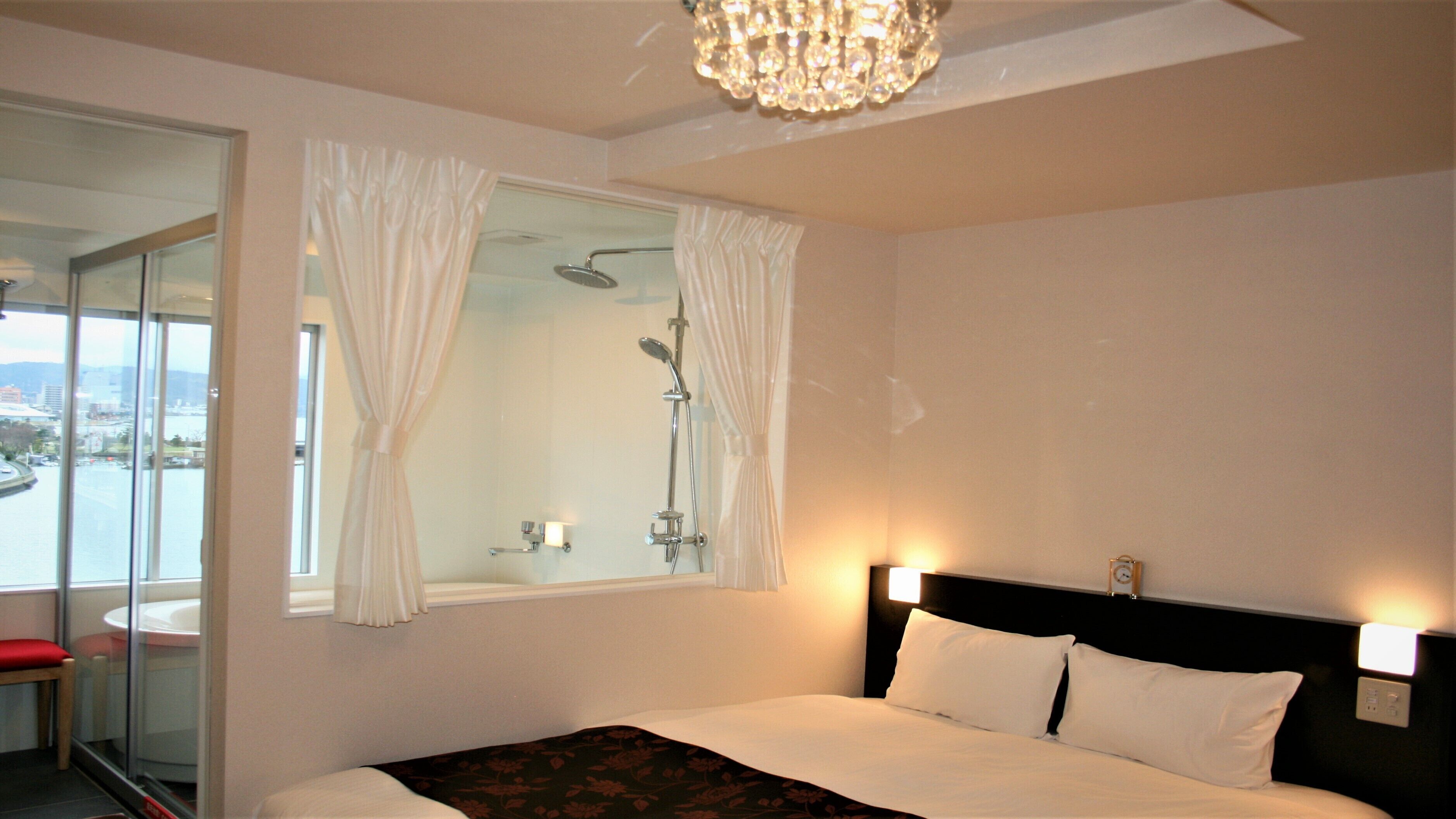 Une chambre d’hôtel avec un lit, une douche, une fenêtre avec des rideaux et une vue sur le paysage urbain.