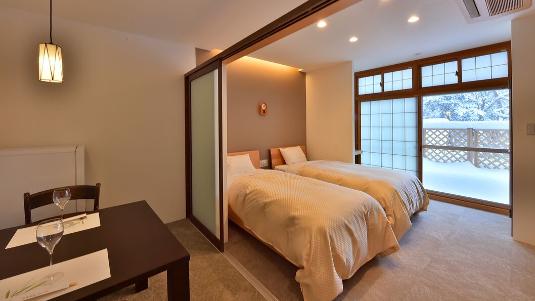 Una habitación de hotel con una cama, una mesa con una copa de vino y vistas de la nieve.