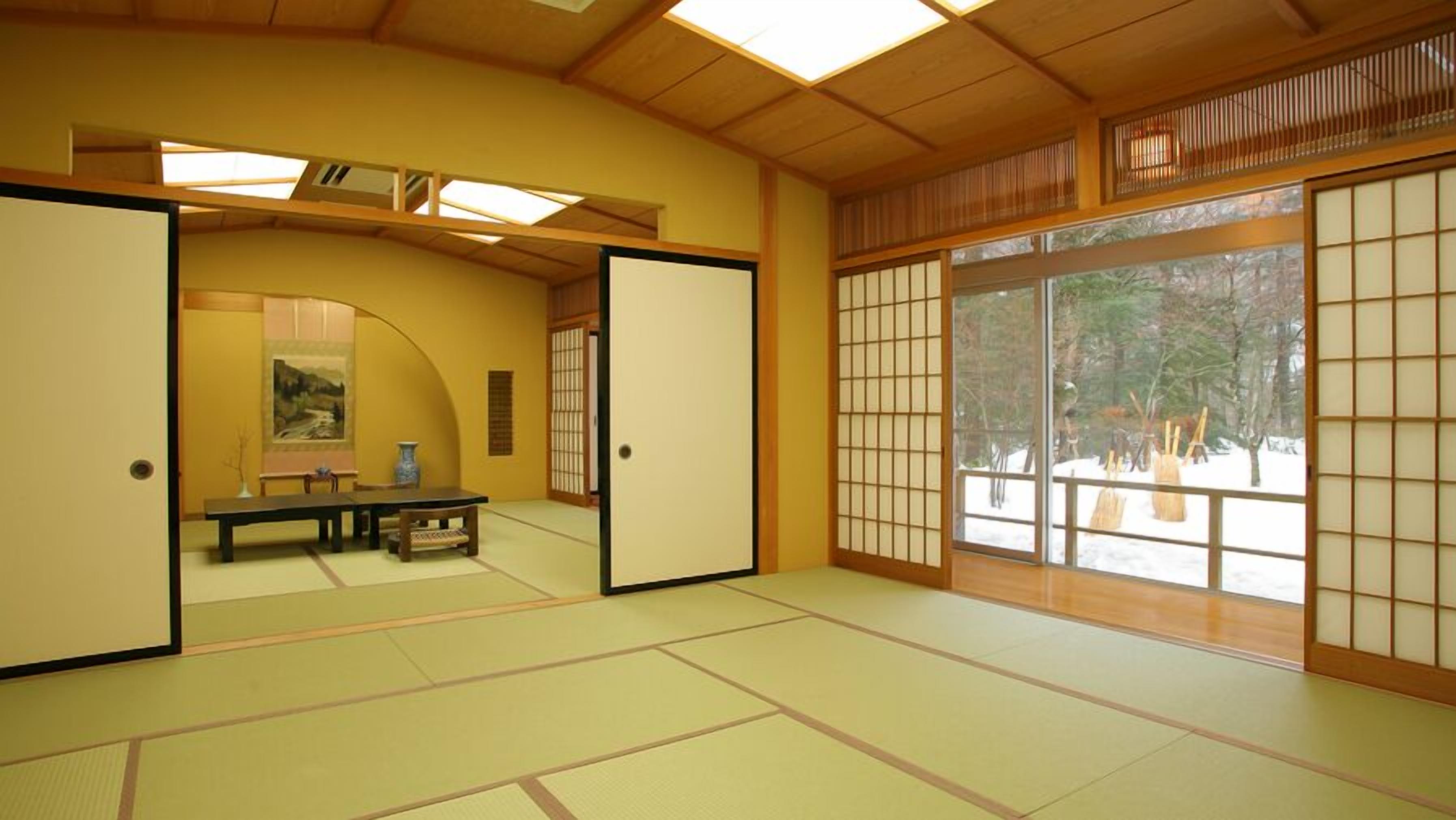 Una habitación tradicional japonesa con suelo de tatami, puertas correderas y un cuadro en la pared.