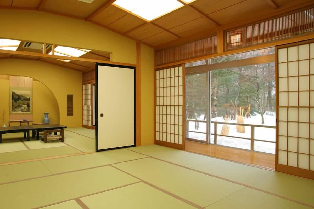 A traditional Japanese room with tatami flooring, sliding doors, and a painting on the wall.