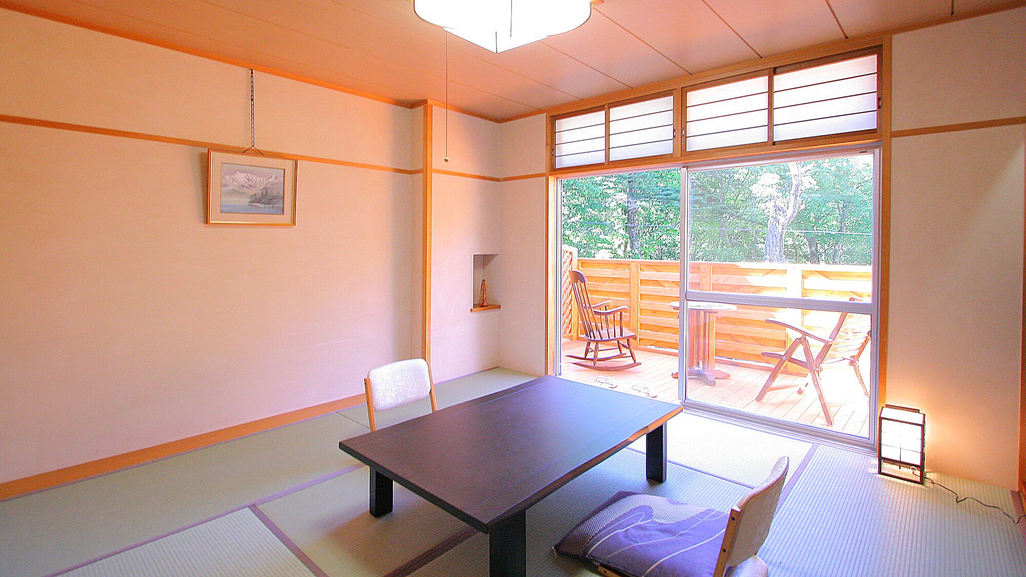 Una habitación con suelo de tatami, una mesa baja, una silla y vistas a una terraza exterior.