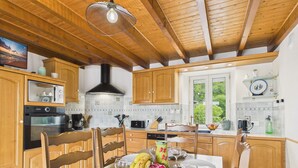 Una cocina con armarios de madera, una mesa de comedor para cuatro personas y un ventanal grande.