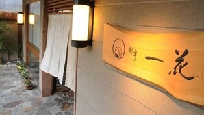 Een houten bord met Japanse karakters, een oprit van stenen plaveisel en een wandlamp.