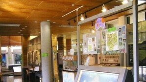 A hallway with wooden ceilings, a stone floor, and informational displays. - Pension Blue Marlin (Hachijo)