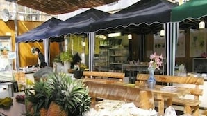 An outdoor market with tables displaying fresh produce and flowers under canopies. - Pension Blue Marlin (Hachijo)