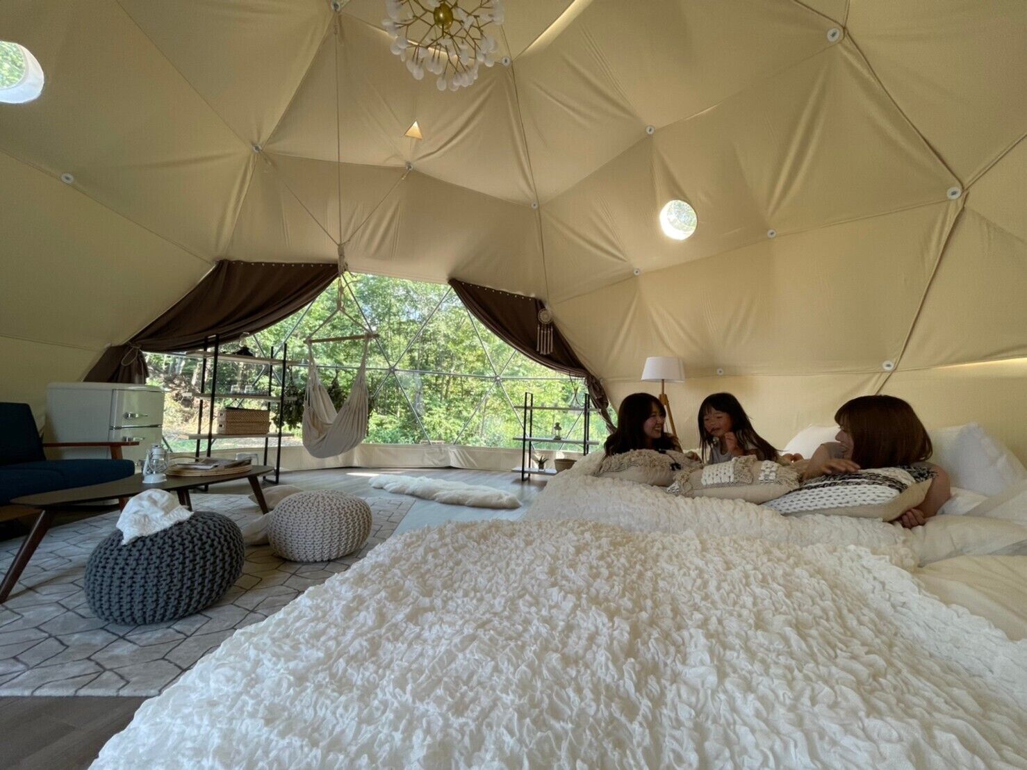 Acomodação em tenda com cama, cadeira suspensa e vista para o verde lá fora.