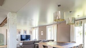 Una sala de estar moderna con comedor, ventanas amplias y un televisor de pantalla plana.