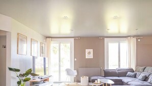 Una sala de estar con un sofá seccional, una silla blanca, una mesita y un radiador.