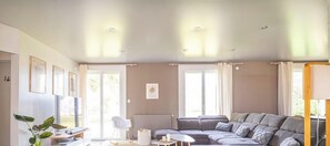 A living room with a sectional sofa, a white chair, a small table, and a radiator. - Family haven & swimming pool - L'Instant Clef (Guécélard)